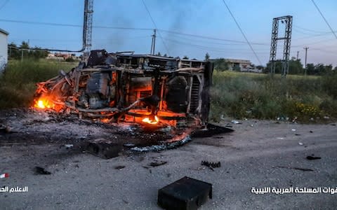 A burning vehicle on the path taken by Haftar's army towards Tripoli - Credit: AFP
