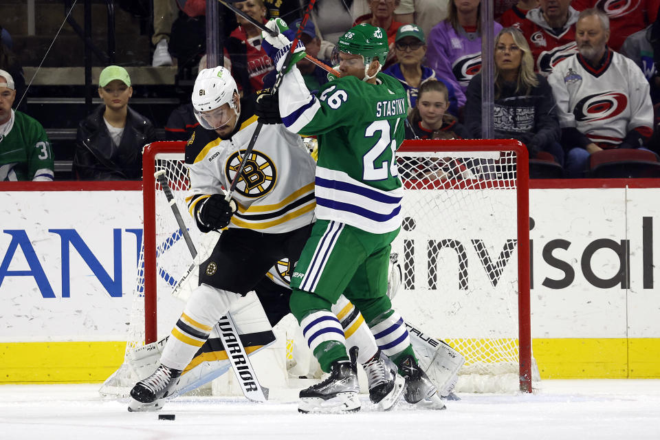 Boston Bruins' Dmitry Orlov (81) battles Carolina Hurricanes' Paul Stastny (26) for the puck during the first period of an NHL hockey game in Raleigh, N.C., Sunday, March 26, 2023. (AP Photo/Karl B DeBlaker)