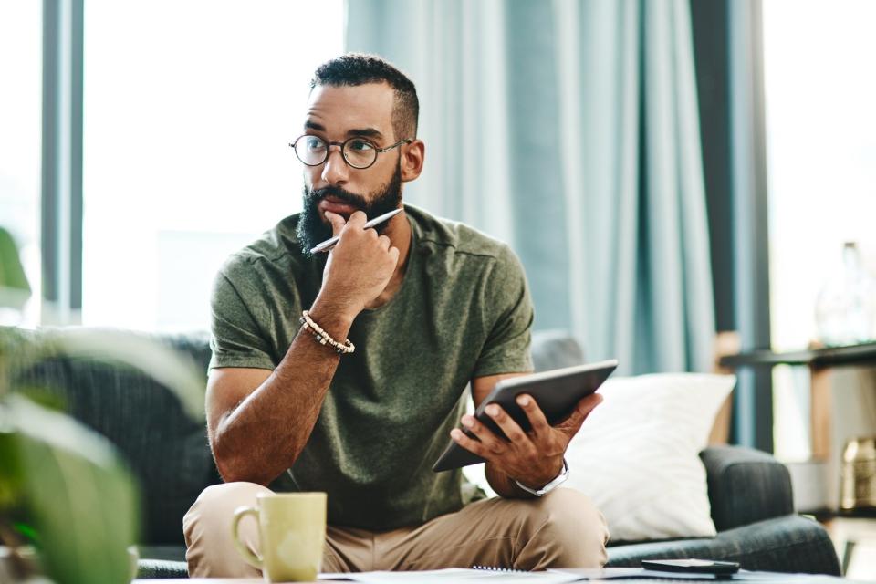 A man holding a tablet with his hand on his chin.