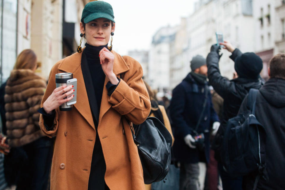 PARIS, FRANCE - JANUARY 25: A model holds an iPhone and thermos after the Jean Paul Gaultier show and wears a green cap, earrings, and a camel peacoat during Couture Spring/Summer 2017 Fashion Week on January 25, 2017 in Paris, France. (Photo by Melodie Jeng/Getty Images)