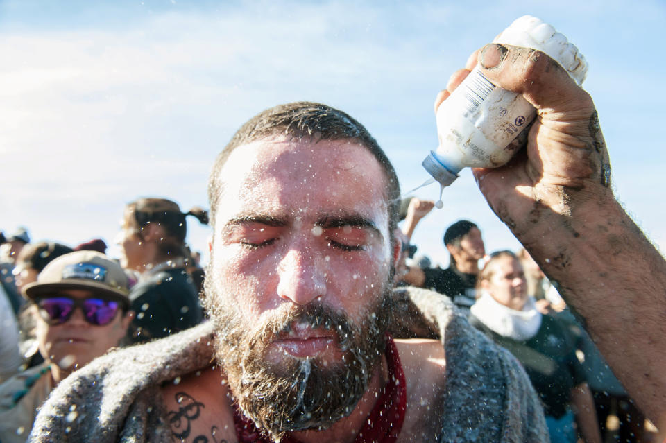 A person pours a pepper spray antidote into a protester's eyes during a protest.