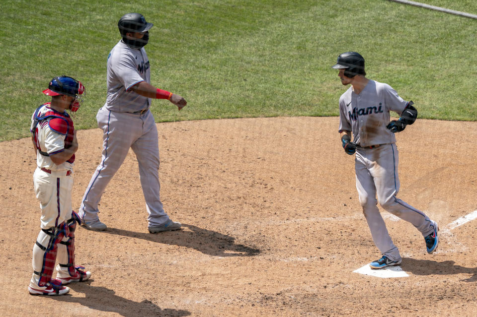 Miami Marlins' Brian Anderson, right, comes in to score on his two-run home run with Jesus Aguilar, center, as Philadelphia Phillies catcher J.T. Realmuto, left, looks on during the fifth inning of a baseball game Sunday, July 26, 2020, in Philadelphia. (AP Photo/Chris Szagola)