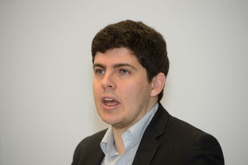 Stock image of Huw Thomas, wearing a blue pinstriped white shirt and black-grey blazer