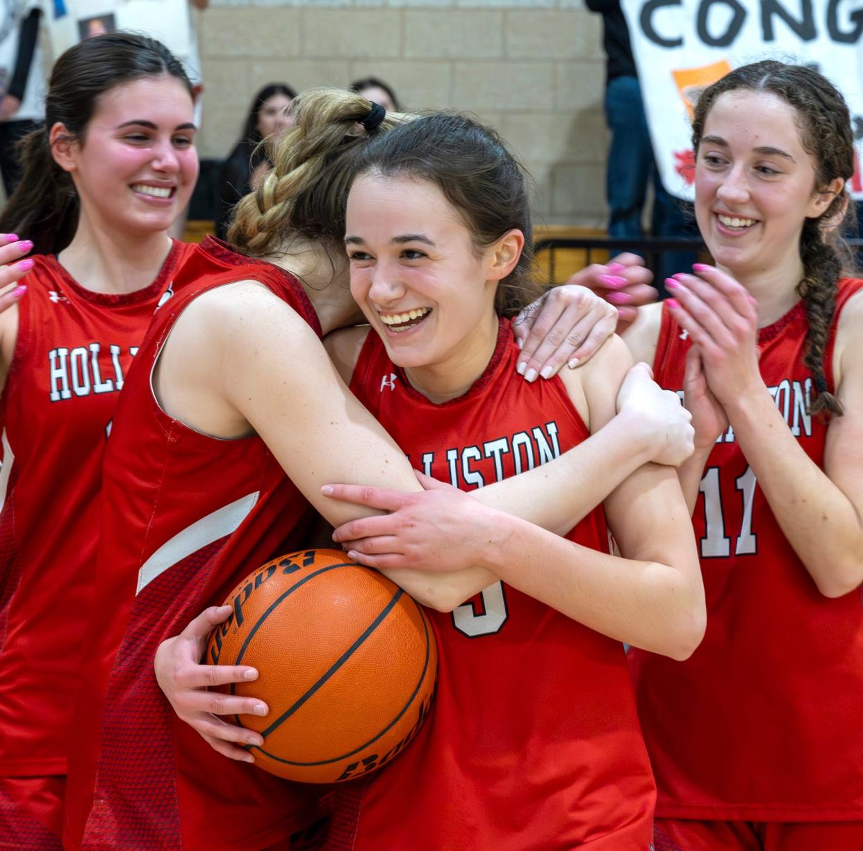 Holliston junior Megan Simpson celebrates scoring her 1,000th career point with her teammates against Norwood on Tuesday in Norwood.