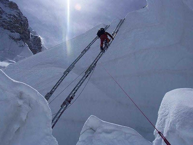 A climber scales a ladder in the Khumbu Icefall