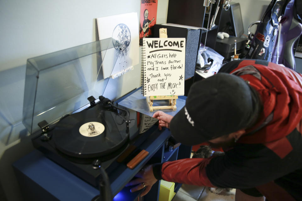 Eli sets up his record player at his home in Casselberry, Fla. on May 29, 2023. He streams music on TikTok and has a GoFundMe to help raise money for him and his fiancé, Lucas, to leave Florida in the next six months. The Associated Press is not using Eli’s and Lucas’ last names because they fear reprisal. Lucas and Eli no longer feel safe living in the state due to recent legislation that targets trans people, including health care and public restroom use. (AP Photo/Laura Bargfeld)