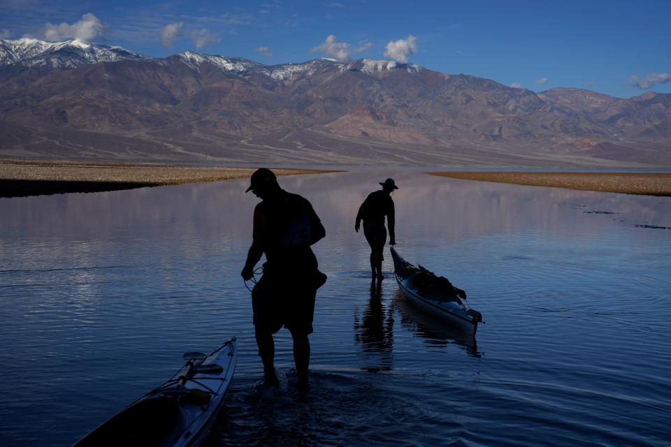 Brian Nelson, left, and Kathleen Nelson, right, both of Bishop, Calif., pull kayaks Thursday into water at Badwater Basin. Record rains and flooding have filled the normally-dry basin with water in the past few months.