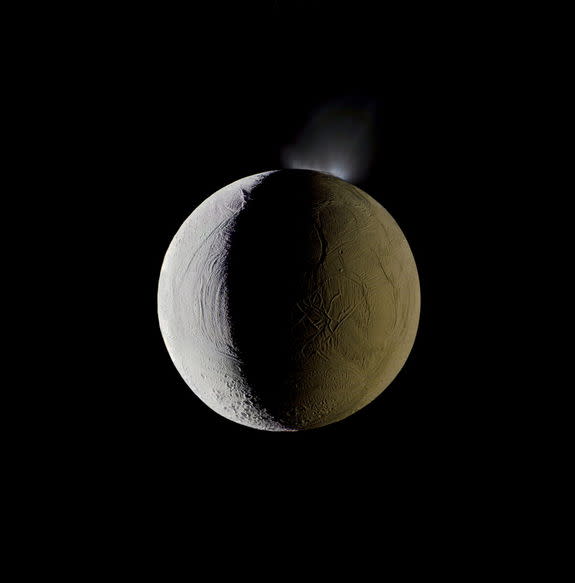 Enceladus vents water into space from its south polar region. The moon is lit by the Sun on the left, and backlit by the vast reflecting surface of its parent planet to the right. Icy crystals from these plumes are likely the source of Saturn's