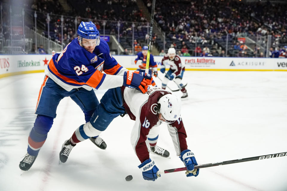 New York Islanders defenseman Scott Mayfield (24) and Colorado Avalanche's Alex Newhook (18) battle for the puck in the first period of an NHL hockey game, Saturday, Oct. 29, 2022, in Elmont, N.Y. (AP Photo/Eduardo Munoz Alvarez)