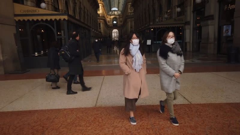 People wearing protective masks walk through the Galleria Vittorio Emanuele shopping centre during rush hour in Milan