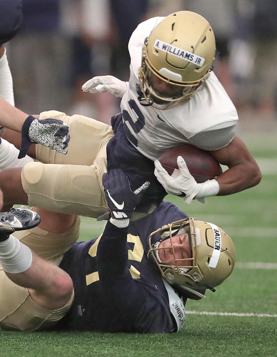 University of Akron linebacker Luke Bauer takes down running back Anthony Williams Jr. during the team's Blue & Gold Spring Game on Saturday at Stile Field House.