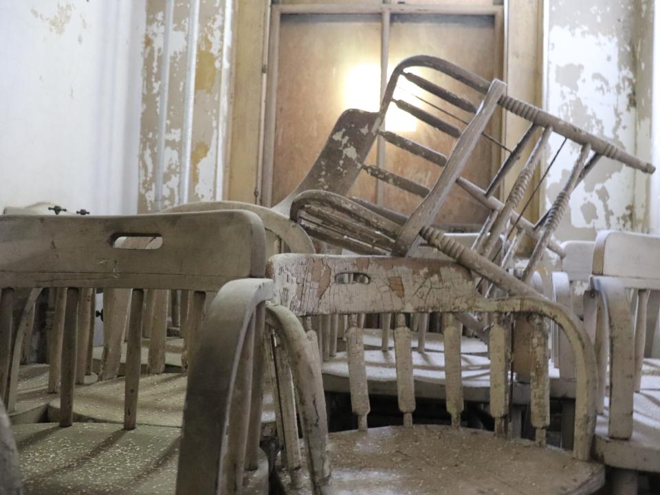 stacks of aging chairs in a room at the ellis island hospital
