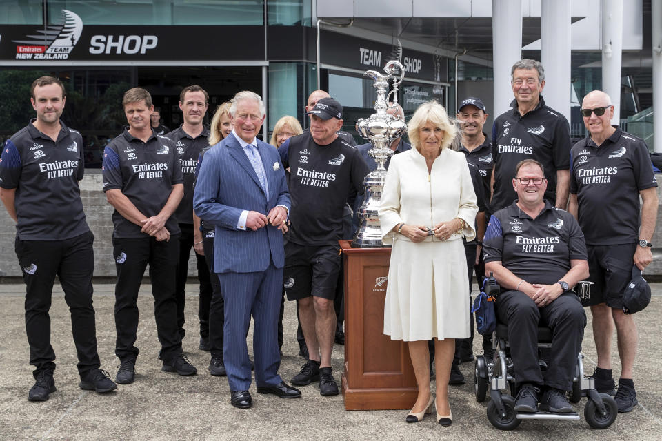 Britain's Prince Charles, fifth left, and his wife Camilla, center, pose for a photo with the America's Cup and members of Team New Zealand during a public walk at Viaduct Harbour in Auckland during their royal visit to New Zealand, Tuesday, Nov. 19, 2019. The visit is part of a week-long tour of the country which also takes in Christchurch and Kaikoura. (David Rowland/Pool Photo via AP)