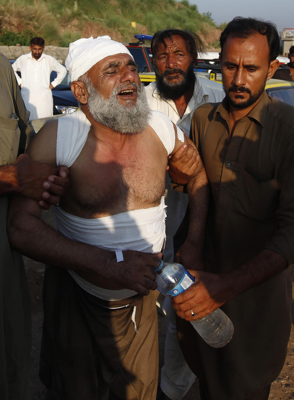 People help an injured victim who morns for the lost of his family member at the site of plane crash in Rawalpindi, Pakistan, Tuesday, July 30, 2019. A small Pakistani military plane crashed into a residential area near the garrison city of Rawalpindi before dawn, killing some people, officials said. (AP Photo/Anjum Naveed)