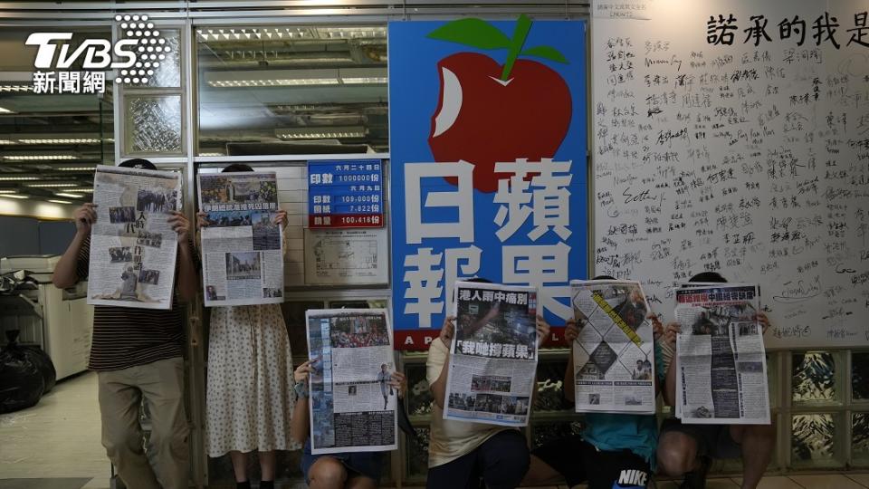 香港《蘋果日報》員工拿著出刊的最後一期報紙，在報社門口合照留念。（圖／達志影像美聯社） 