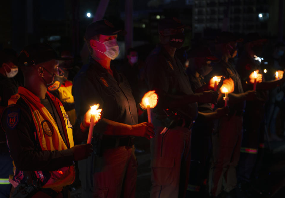 Frontline workers attend a candlelight ceremony on New Year's Eve on the famed Nelson Mandela Bridge in downtown Johannesburg Thursday, Dec. 31, 2020. Many South Africans will swap firecrackers for candles to mark New Year's Eve amid COVID-19 restrictions including a nighttime curfew responding to President Cyril Ramaphosa's call to light a candle to honor those who have died in the COVID-19 pandemic and the health workers who are on the frontline of battling the disease.. (AP Photo/Denis Farrell)