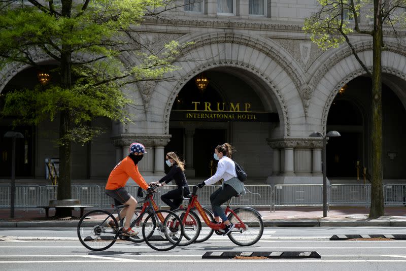 Bicyclists wearing masks pass the Trump Hotel in Washington