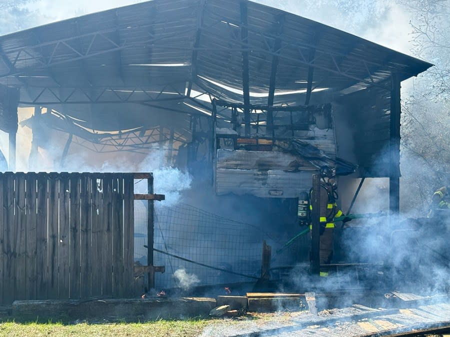 Burned camper under large metal barn