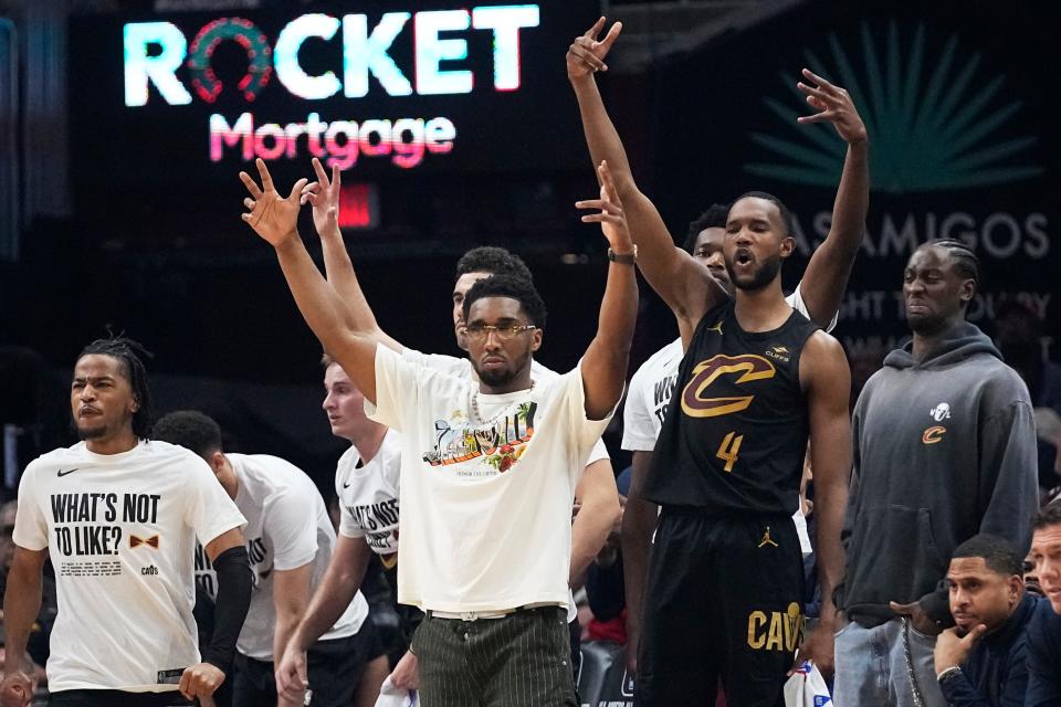 Cleveland Cavaliers' Donovan Mitchell, center, and Evan Mobley (4) cheer in the bench area in the first half of an NBA basketball game against the New York Knicks, Sunday, March 3, 2024, in Cleveland. (AP Photo/Sue Ogrocki)