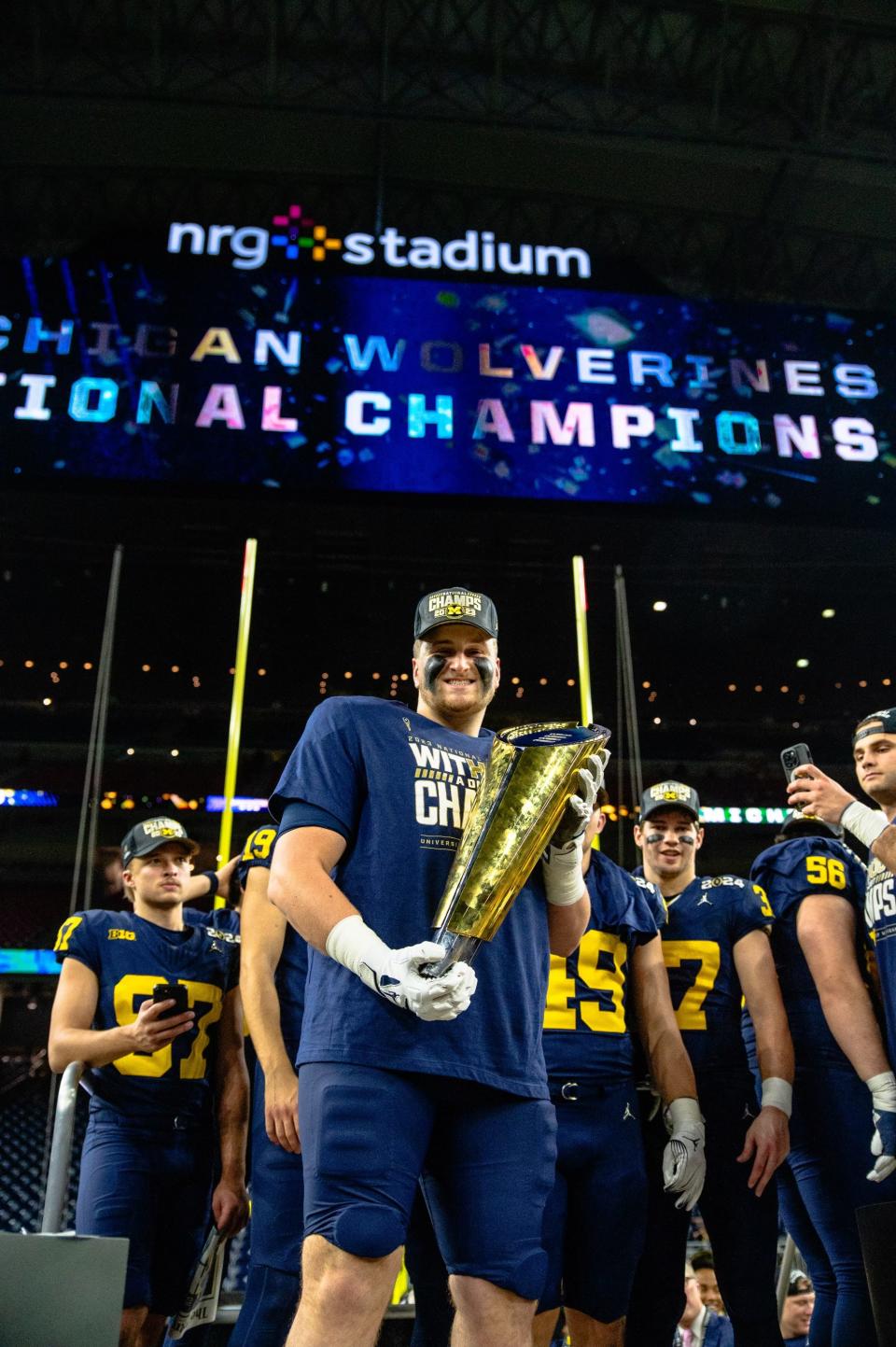 Peter Simmons III hold the CFP National Championship trophy following Michigan's 34-13 win over No. 2 Washington