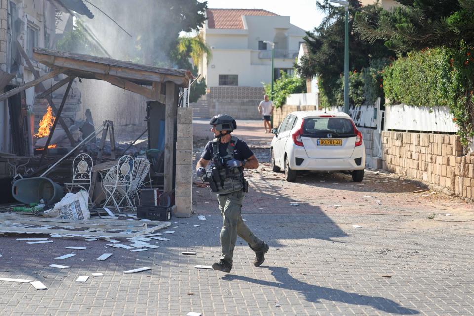 October 7, 2023: A member of the Israeli forces runs past a fire raging in a house in Ashkelon following a rocket attack from the Gaza Strip on southern Israel. Palestinian militant group Hamas has launched a "war" against Israel, Defence Minister Yoav Gallant said, after barrages of rockets were fired from the Gaza Strip into Israeli territory.