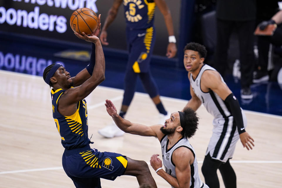 Indiana Pacers guard Caris LeVert, left, shoots over San Antonio Spurs guard Derrick White, center, during the first half of an NBA basketball game in Indianapolis, Monday, April 19, 2021. (AP Photo/Michael Conroy)