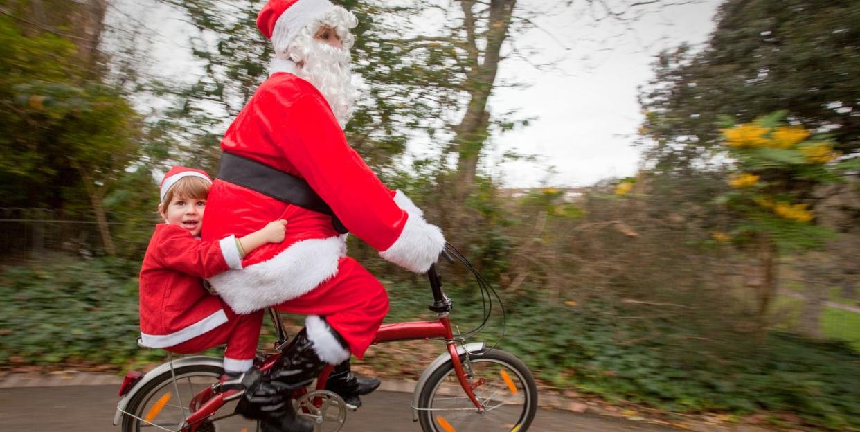 mother and son dressed as santa claus on a bicycle