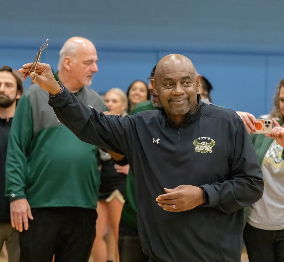 GlenOak boys basketball head coach Rick Hairston holds up scissors in preparation of the net being cut after defeating Louisville in a district final, Saturday, March 9, 2024, at Alliance.