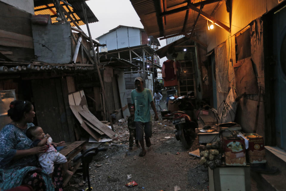 In this Tuesday. Oct. 15, 2019, photo, a man walks on an alley at a slum in Jakarta, Indonesia. Known for his down-to-earth style with a reputation for clean governance, Indonesian President Joko Widodo's signature policy has been improving Indonesia's inadequate infrastructure and reducing poverty, which afflicts close to a tenth of Indonesia's nearly 270 million people. But raising money would be harder at a time of global economic slowdown, major trade conflicts and falling exports. (AP Photo/Tatan Syuflana)