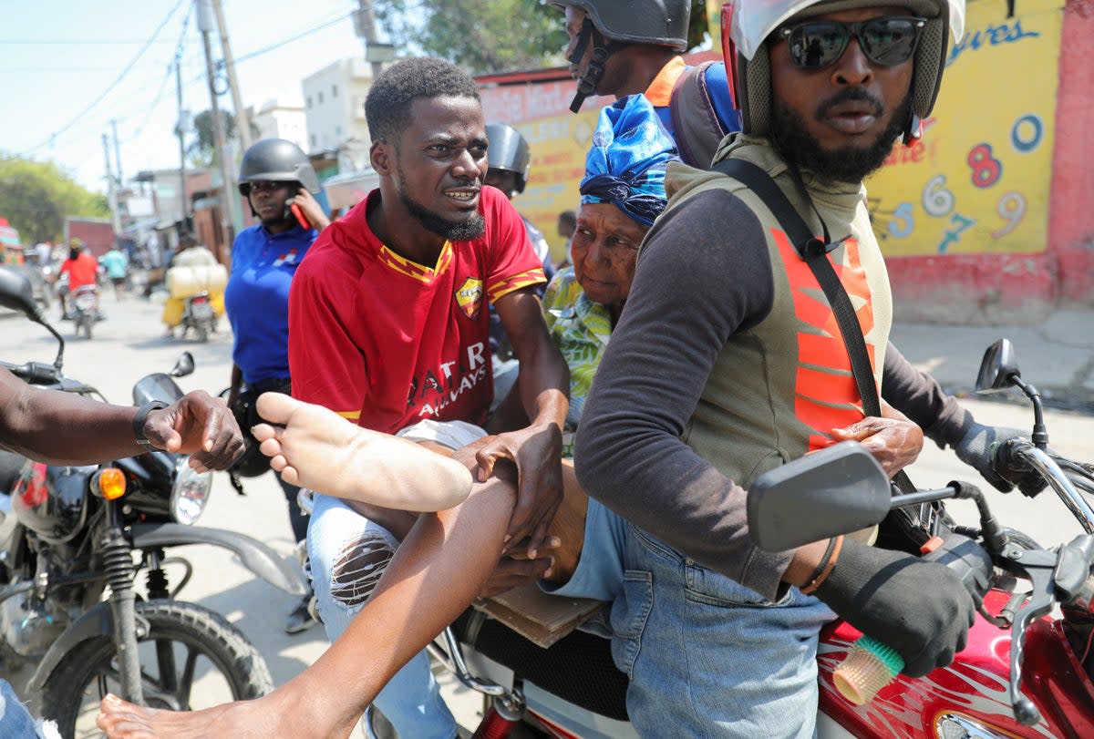 A woman with a gunshot wound is transported on a motorcycle in Port-au-Prince (Reuters)