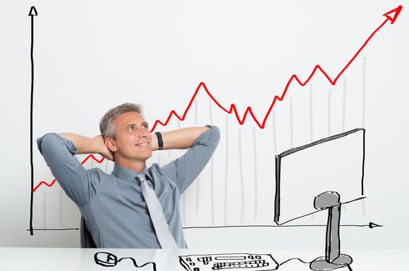 A businessman watches a chart of rising returns.