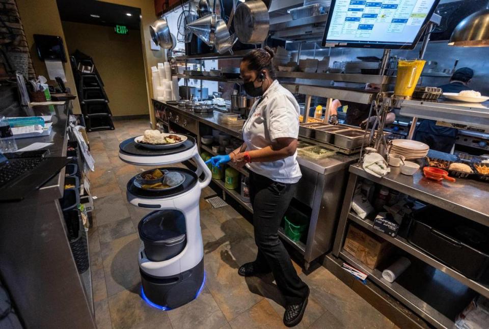 Yei Alayo, a worker in the kitchen at Sergio’s restaurant in Kendall, programs a Servi robot server to deliver an order to a specific table inside the dining room, on May 21, 2021. This particular Servi robot was renamed ASTRO.