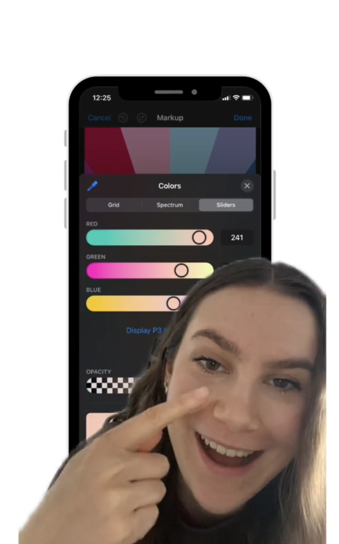 A woman smiles and points at her cheek, with a phone screen in the background showing a color selection tool on a drawing app