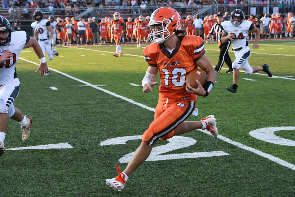 Heath junior quarterback Brayden Bayles runs along the sideline against visiting Liberty Union during the season opener at Swank Field on Friday, Aug. 19, 2022. Bayles ran for the game-winning touchdown as the Bulldogs stunned the visiting Lions 28-27.