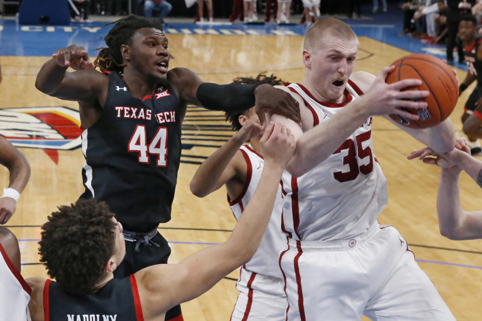 Oklahoma forward Brady Manek (35) grabs a rebound in front of Texas Tech guard Chris Clarke (44) and guard Clarence Nadolny, left, in the second half of an NCAA college basketball game Tuesday, Feb. 25, 2020, in Oklahoma City. (AP Photo/Sue Ogrocki)