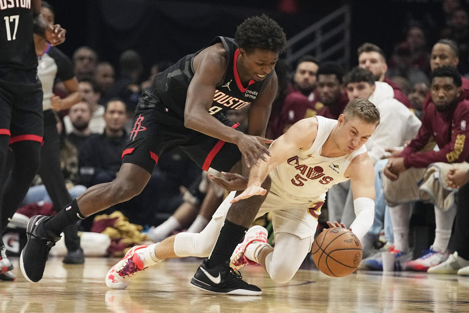 Houston Rockets forward Jae'Sean Tate, left, and Cleveland Cavaliers guard Sam Merrill (5) dive for the ball in the first half of an NBA basketball game, Monday, Dec. 18, 2023, in Cleveland. (AP Photo/Sue Ogrocki)