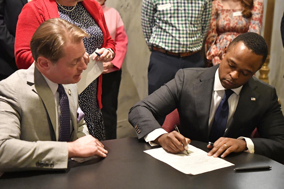 As Kentucky Secretary of State Michael Adams, left, looks on, Kentucky Attorney General David Cameron signs the documents officially entering the race for Governor in Frankfort, Ky., Tuesday, Jan. 3, 2023. (AP Photo/Timothy D. Easley)