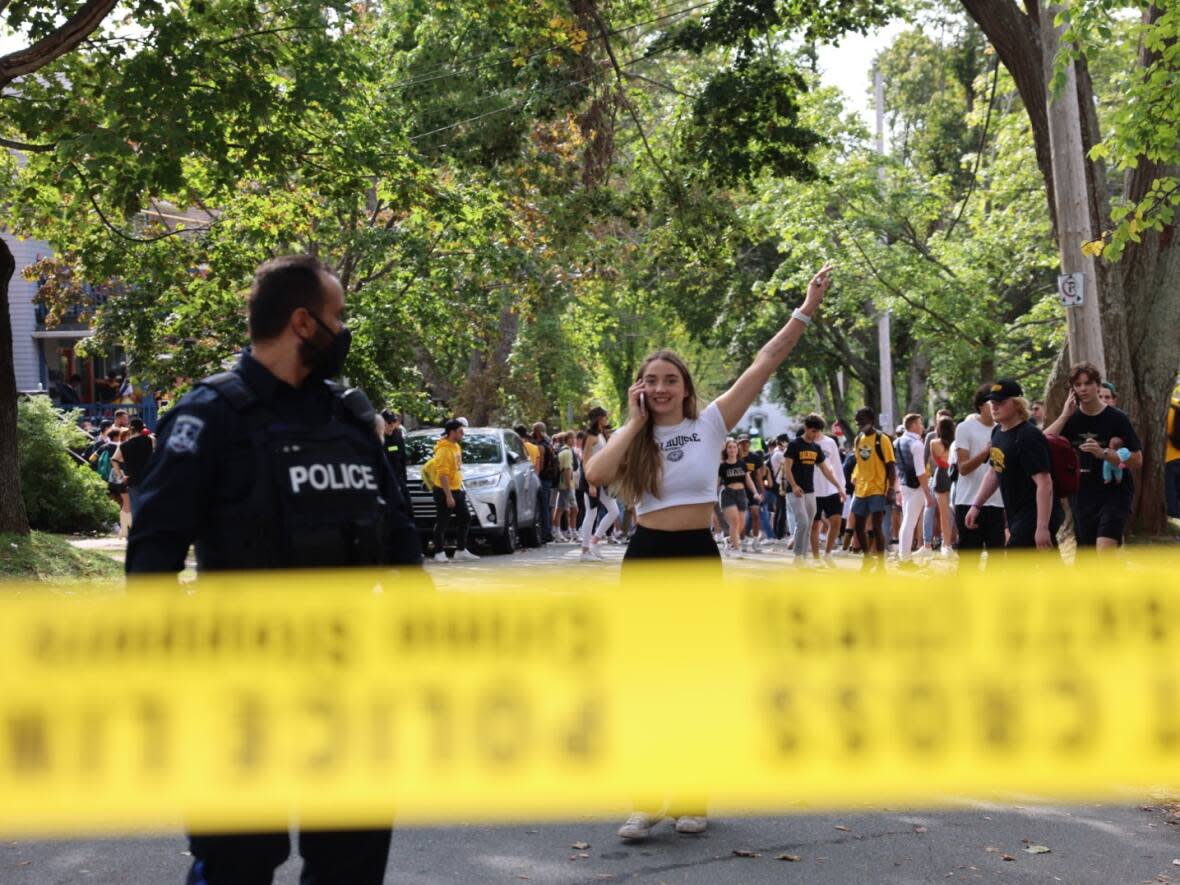 A jubilant reveler behind police tape on Jennings Street in Halifax during a student street party in September 2021. (Jeorge Sadi/CBC - image credit)