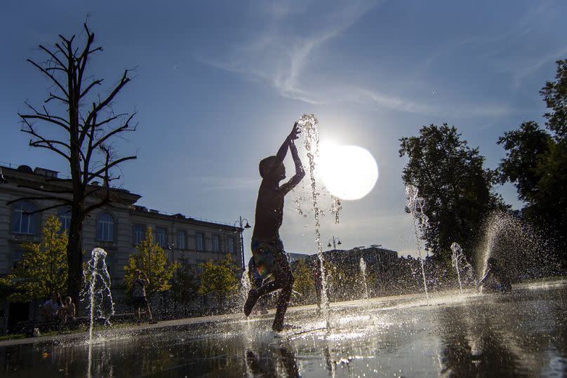 Un niño se refresca en una fuente pública en Vilnius, Lituania.