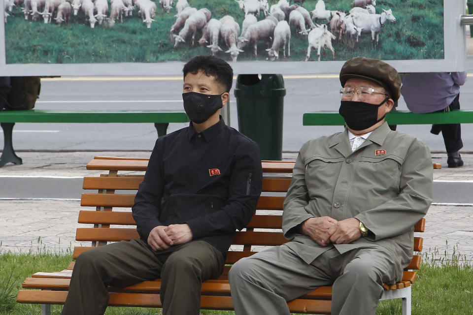 People in a park wearing masks watch news broadcasted on a giant screen showing leader Kim Jong Un attending the opening ceremony of the Sunchon Phosphatic Fertilizer Factory Saturday, May, 2nd. 2020, in Pyongyang, North Korea. Un made his first public appearance in 20 days as he celebrated the completion of a fertilizer factory near Pyongyang, state media said Saturday, ending an absence that had triggered global rumors that he may be seriously ill. (AP Photo/Jon Chol Jin)