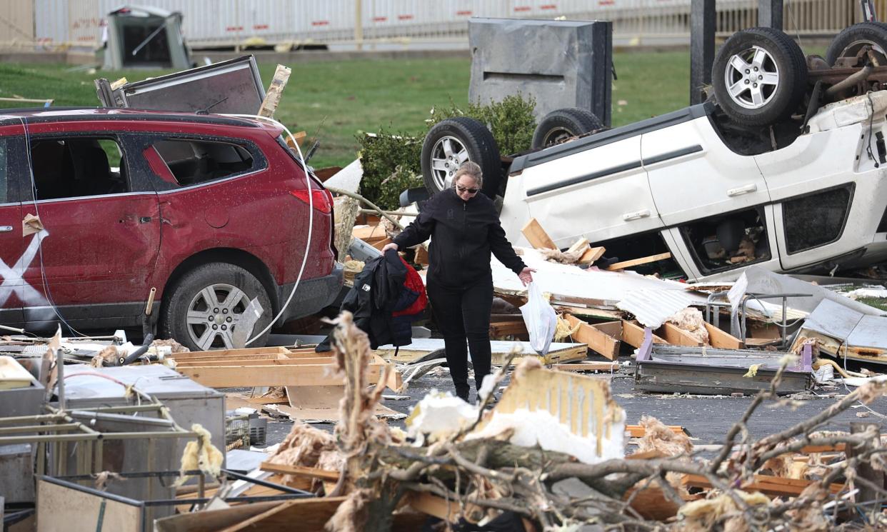 <span>A woman walks through debris piled up outside a restaurant destroyed by a tornado on 15 March in Winchester, Indiana. </span><span>Photograph: Scott Olson/Getty Images</span>