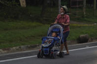 A migrant pushes a stroller along the highway toward the municipality of Escuintla, Chiapas state, Mexico, early Thursday, Oct. 28, 2021, as she walks with a group of migrants toward the northern states of Mexico and the U.S. border. (AP Photo/Marco Ugarte)