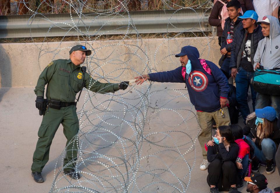 A Customs and Border Protection agent speaks to a migrant that had crossed the Rio Grande and approached the Texas National Guard to enquire when they will be allowed to be processed by Customs and Border Protection to seek asylum in El Paso, Texas on Dec. 20, 2022.