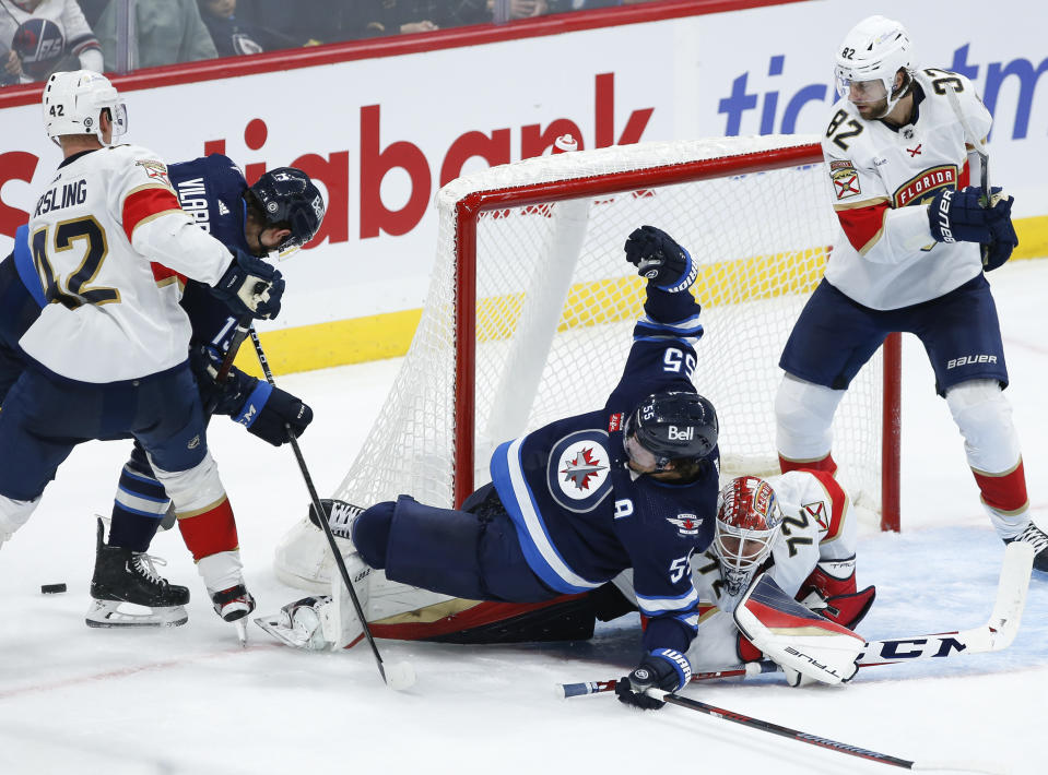 Winnipeg Jets' Mark Scheifele (55) crashes into Florida Panthers goaltender Sergei Bobrovsky (72) as Panthers' Kevin Stenlund (82) defends during third-period NHL hockey game action in Winnipeg, Manitoba, Saturday, Oct. 14, 2023. (John Woods/The Canadian Press via AP)