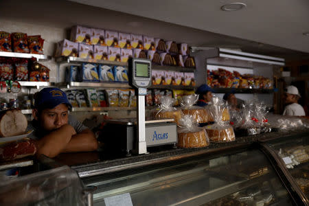 A vendor waits in darkness inside a bakery, during a massive blackout in Caracas, Venezuela December 18, 2017. REUTERS/Marco Bello