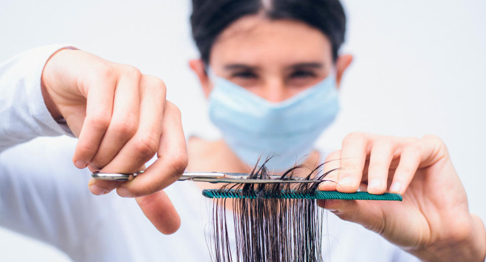 A women in a mask cutting hair. Source: Getty Images 