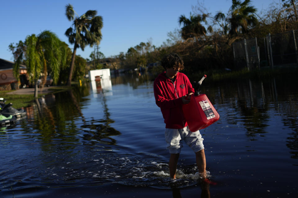 FILE - Jose Cruz, 13, carries an empty jerrycan through receding flood waters outside his house as his family heads out to look for supplies, three days after the passage of Hurricane Ian, in Fort Myers, Fla., Oct. 1, 2022. Hurricane Ian confounded one key computer forecast model, creating challenges for forecasters and Florida residents. (AP Photo/Rebecca Blackwell, File)