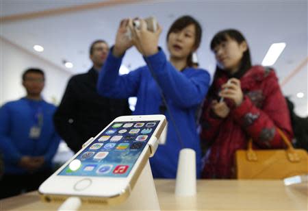 A staff of a China Mobile shop explains a function of the iPhone 5s to a customer in Beijing January 17, 2014. REUTERS/Kim Kyung-Hoon