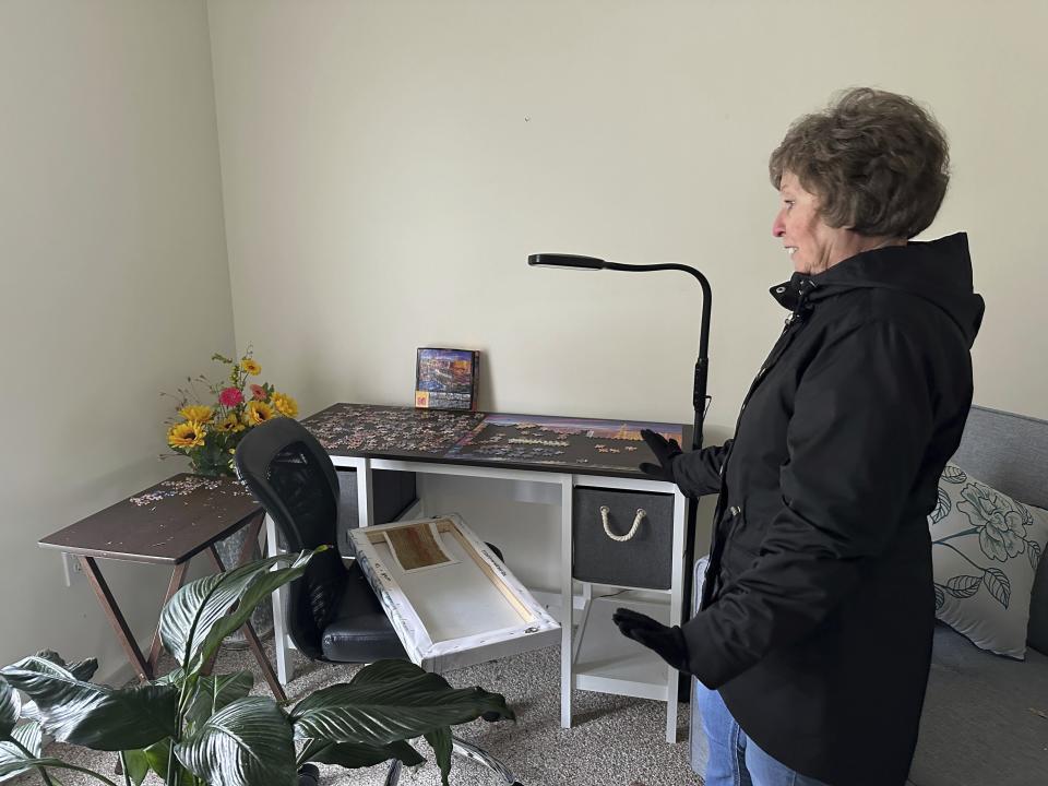 Romona Platt, 81, shows a jigsaw puzzle in her home that she was surprised to see still intact in Winchester, Ind., on Friday, March 15, 2024. A Thursday night storm damaged the roof of her home and shattered the window of her room where she works on puzzles. She had taken shelter in a bathroom. (AP Photo/Isabella Volmert)