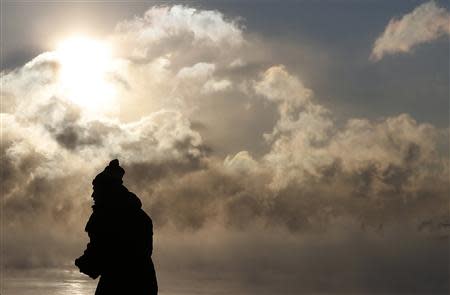 A man is silhouetted against the sun and arctic sea smoke rising off Lake Michigan in Chicago, Illinois January 6, 2014. REUTERS/Jim Young